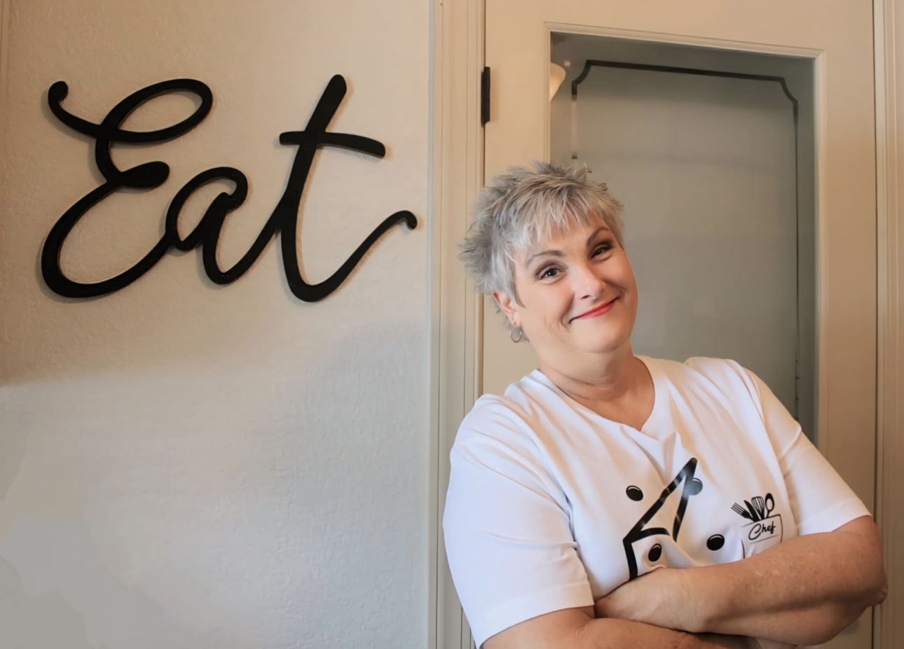 Colleen smiling beside an Eat sign
